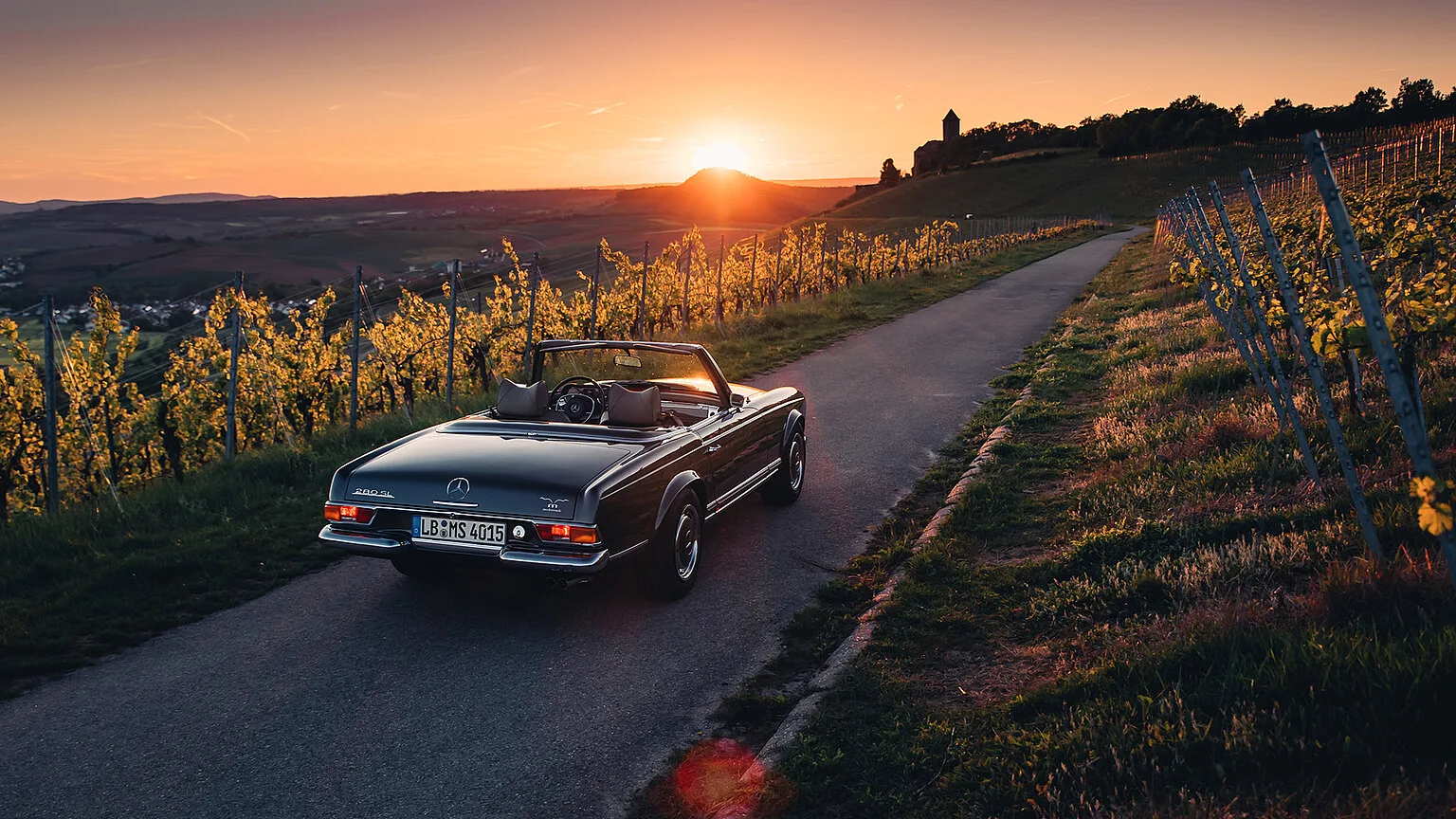 Klassische Mercedes Pagode auf einer Landstraße durch die Weinberge bei Sonnenuntergang
